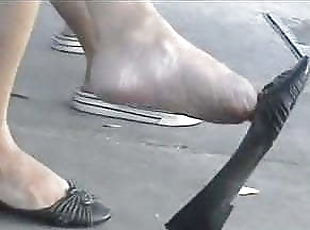 Candid asian dangling shoes at bus stop