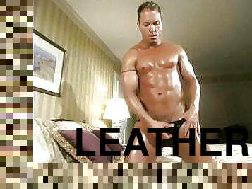 Muscle stud in a leather thong rubbing oil in his body