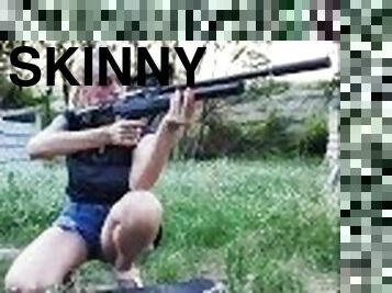 Cute skinny girl on a skateboard shoots a sniper rifle