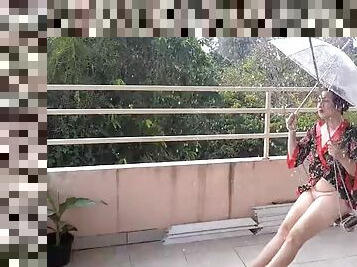 The lady swings on a hanging swing, hiding from the rain under an umbrella