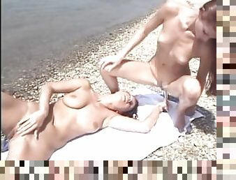 Teen girls are fucking each other with a clear dildo on the beach